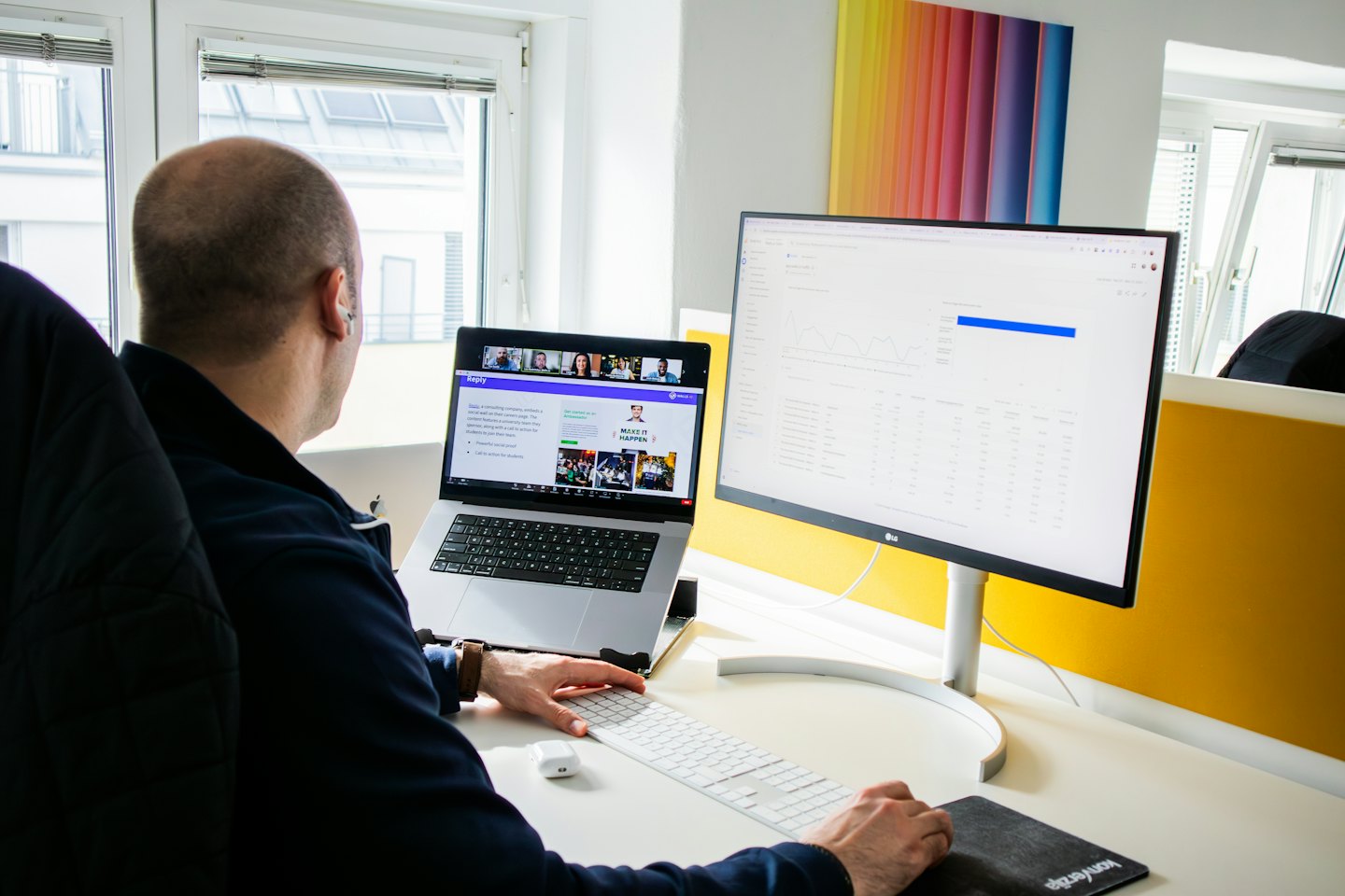 Man arbetar vid laptop och monitor på ett modernt kontor.